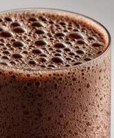 Thick and creamy chocolate protein shake topped with frothy bubbles photo