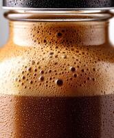 Protein shake in a glass jar with frothy surface and condensation photo