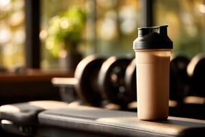 Protein shake resting on a bench in a bright gym during a workout session photo
