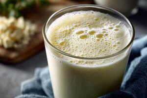 A fresh protein shake fills a clear glass, showcasing a frothy top photo