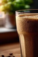 Protein shake in a glass sitting on a wooden table by a window photo