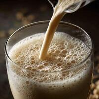 Pouring a creamy protein shake into a glass with frothy texture photo