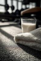 Protein shake on gym floor beside towel in bright training space photo