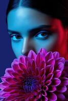 Model holds a vibrant flower while posing in dramatic lighting photo