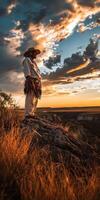 Traditional dancer standing on a rock at sunset in the mountains photo