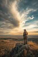 Man standing atop rock in vast landscape during sunset photo