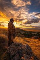 Man in traditional attire admires sunset over a vast landscape photo