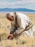 Elderly man tending to grasslands in a vast desert landscape photo