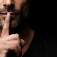 Man gestures for silence with a finger on his lips photo