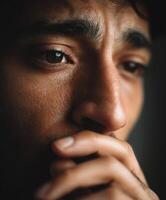 Close-up of a young man reflecting deeply in a dimly lit room photo