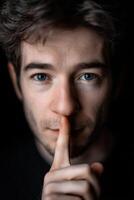 Close-up of a man making a shushing gesture indoors photo