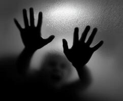 Child trapped behind a frosted glass door reaching out for help photo
