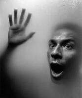 Person behind fogged glass looking surprised and frightened photo