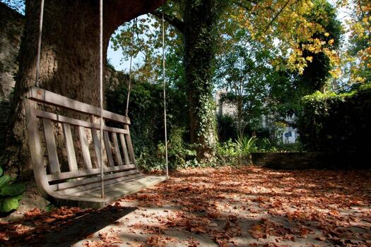 Scenic swing under a tree surrounded by colorful autumn leaves photo