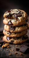 Chocolate chip cookies stacked on wooden table with pieces around photo
