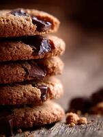 Soft chocolate chip cookies stacked on a rustic wooden surface photo