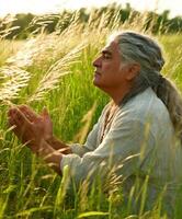 Man meditating in a lush green field at sunset with a peaceful expression photo