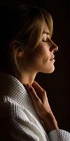 Woman in a robe meditating with closed eyes in a dimly lit space photo