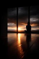 Silhouetted figure watches sunset through large windows in a serene setting photo