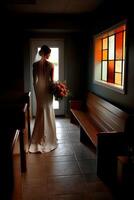 Bride in elegant wedding dress stands by window before ceremony photo