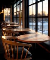 Elegant wooden tables and chairs by large windows during sunset hours photo