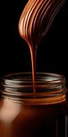 Chocolate sauce drizzled from a whisk into a glass jar at a kitchen photo