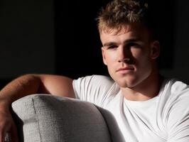 Young man posing casually on a sofa in soft natural light indoors photo