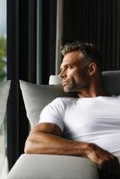 Man relaxing indoors while gazing out at sunlight during afternoon photo