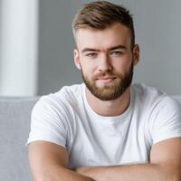 Young man with beard sitting casually indoors in natural light photo