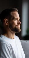 Man with beard gazes thoughtfully out a window in natural light photo