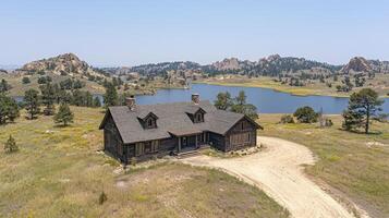 A cabin in the middle of a field with a lake in the background photo