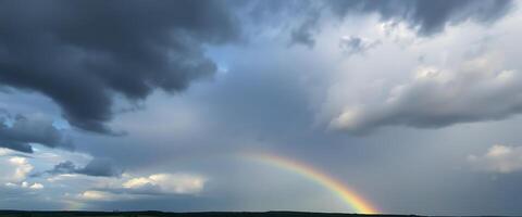 rainbow in a cloudy sky over a field photo