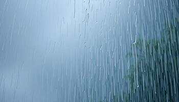 rain falling down on a window with a tree in the foreground photo