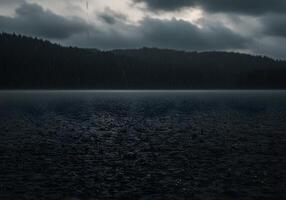 A dark lake with rain falling over it photo