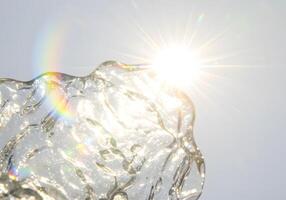 A close up of a clear ice cube with the sun shining through photo
