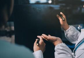 A woman in a lab coat is writing on a black board photo