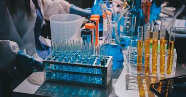 A person in a lab coat is working on a table with many different colored liquids photo
