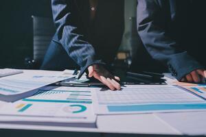 Two business people are working on a table with papers and graphs photo