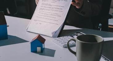 A person is holding a piece of paper with a house on it and a pen in her hand photo