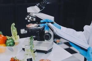 A person in a lab coat is holding a clipboard and looking at a microscope photo
