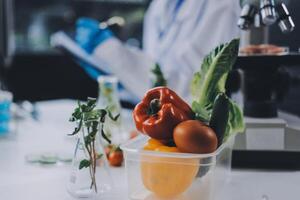 A scientist is holding a microscope and a container with vegetables photo