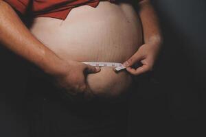 A man with a large belly measuring his waist photo