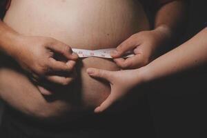 A man is measuring his stomach with a tape photo