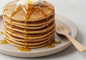 Stack of pancakes with syrup and banana slice on a plate photo