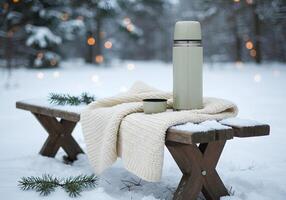 Snowy bench with thermos and blanket photo