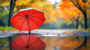 A red umbrella is reflected in a puddle of water photo