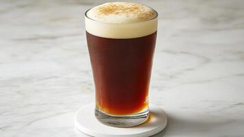 A tall glass of beer sitting on a marble surface photo
