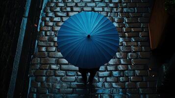 A person walking down a cobblestone street with a blue umbrella photo