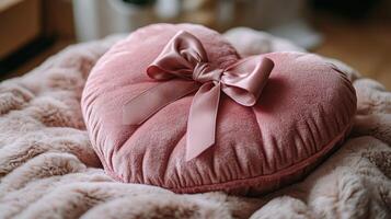 A pink heart shaped pillow with a bow on it photo