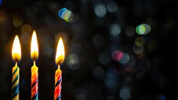Three lit candles are in front of a dark background photo
